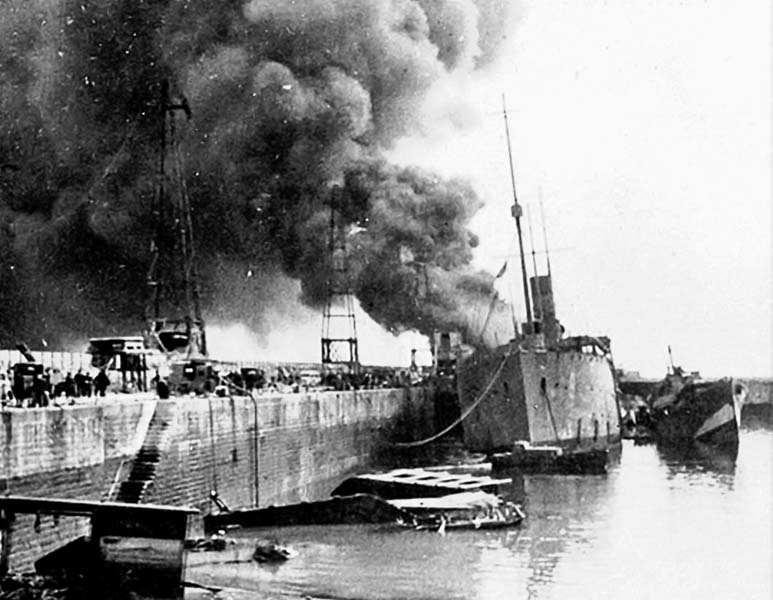 Among the damage caused by the German bombing raid on Dover on July 29, 1940, the Royal Navy depot ship HMS Sandhurst was hit and set on fire at the quay side. She was carrying ammunition and torpedoes, which could have caused a massive explosion, but fortunately the fires were extinguished and she was patched up sufficiently to be towed away for repairs. (Photo author’s collection)