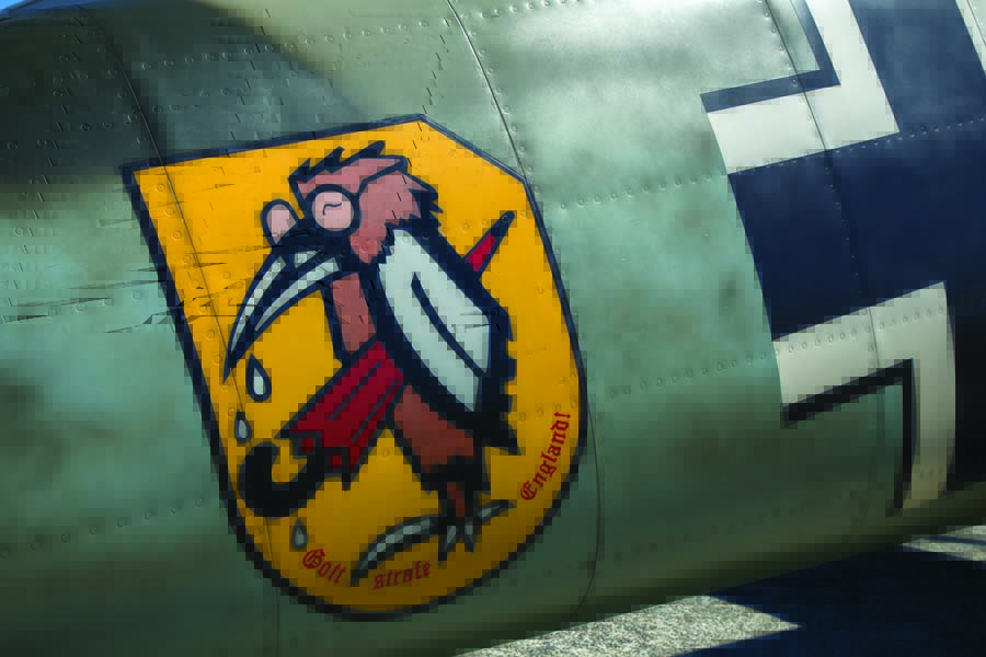 The JG 51 emblem was painted on all of the unit’s Bf 109s: a verschnupfte rabe (“runny-nosed raven”), wearing glasses and holding an umbrella, with the phrase “Gott Strafe England” (“May God Punish England”) (Photo by John Dibbs/Facebook.com/theplanepicturecompany)